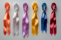 Colorful satin awareness ribbons arranged in row on light background - orange, white, purple, yellow, blue and red silk ribbons with knots for social causes.