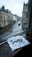 Crumpled note with the word Sorry on a rainy window sill, conveying regret, apology, and emotional sadness on a gloomy urban day.