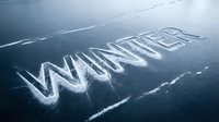 Word winter carved in snow and ice on a frozen lake surface, cold blue tones, seasonal concept for holiday and weather design.