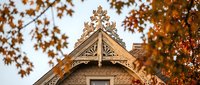 Victorian gingerbread house with ornate wooden trim and decorative bargeboard details framed by autumn foliage for architectural design projects.