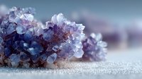 Purple amethyst crystal cluster on sparkling white surface with soft blurred background, showcasing natural mineral formation with translucent facets.