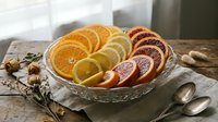 Fresh citrus fruit slices arranged on glass plate including orange, lemon and blood orange with spices on rustic wooden table for healthy eating.