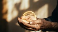 Elderly hands holding a glowing golden energy sphere, warm light and shadows in background, symbolizing wisdom, power, and spiritual energy.