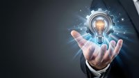 Businessman hand holding glowing light bulb with gear mechanism representing innovation and creative business solutions for technology development.