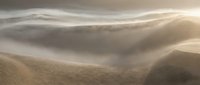Misty mountain landscape with rolling hills and soft morning light creating atmospheric layers of fog and golden sunbeams across peaceful valley terrain.
