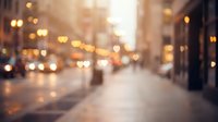 Blurred urban street scene with warm golden bokeh lights creating dreamy atmosphere during golden hour for backgrounds and design projects.