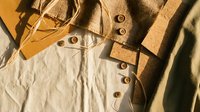 Vintage leather apron and work tools on textured fabric background. Artisan craftsmanship concept for workshops, handmade projects and traditional trades.