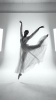 Graceful ballerina in flowing dress performs elegant leap in modern studio space. Black and white artistic dance photography capturing movement and expression.