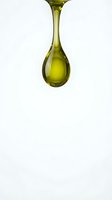 Golden olive oil drop falling on white background isolated for culinary cooking healthy nutrition organic food ingredient design.