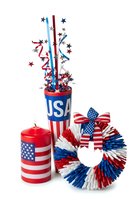 Patriotic USA decorations featuring red, white and blue centerpiece with star bursts, flag-themed candle and festive wreath isolated on white background for holiday celebrations and events.