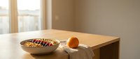Wooden table with golden bowl containing colorful beads, amber glass sphere, and linen cloth near sunlit window for interior design and lifestyle projects.