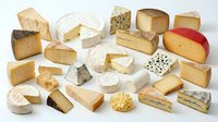 Assorted gourmet cheese collection featuring various textures and types including soft brie, aged cheddar, blue cheese and artisanal varieties on white background.