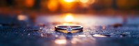 Elegant diamond engagement ring on reflective surface with golden bokeh lights creating romantic atmosphere. Wedding proposal concept.