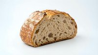 Artisan sourdough bread loaf with crusty exterior and open crumb structure, sliced to show interior texture. Use for bakery, food, culinary, and restaurant marketing.