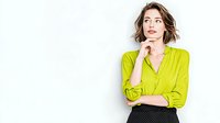 Young woman in bright lime green blouse with thoughtful expression against white background, perfect for business or fashion content.