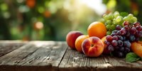 Fresh seasonal fruits arranged on rustic wooden table with soft bokeh background, showcasing peaches, oranges, and grape clusters in natural light.