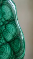 Polished malachite stone with vibrant green concentric rings and swirled patterns showcasing natural mineral formation and geological beauty for luxury decor.