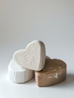 Handmade heart-shaped soap bars in natural beige and white colors with organic texture, artisan skincare products for spa and wellness routines.