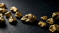 Golden metal nuggets scattered on dark slate surface creating luxury wealth concept for investment and mining industry backgrounds.