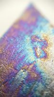Iridescent holographic surface with rainbow colors and metallic sheen creating abstract prismatic reflections and optical illusion effects for modern design projects.