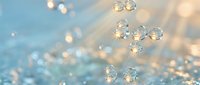 Sparkling crystal water droplets floating in soft golden sunlight with glowing bokeh background, creating a dreamy, luminous atmosphere.