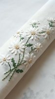 Delicate white daisy flowers hand embroidered on natural linen fabric with green stems and leaves creating elegant floral needlework design for crafting projects.