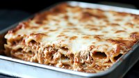 Homemade meat lasagna with melted mozzarella cheese layers, ground beef and tomato sauce in baking dish, close up view of traditional Italian pasta dish.