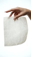 Elegant female hand gently touching soft white textured material on clean background for skincare and beauty concepts.