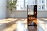 Artistic wooden resin block catching sunlight on wooden surface, showcasing natural amber tones and organic patterns in minimalist interior setting.
