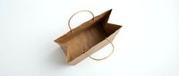 Empty brown kraft paper shopping bag with handles open on white background isolated for retail packaging and eco-friendly commercial design projects.