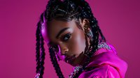 Young woman with braided hairstyle in pink hoodie against vibrant magenta background, dramatic side lighting creates modern urban portrait with neon aesthetic.