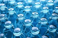 Rows of empty blue glass bottles with metal caps arranged in repetitive pattern, creating abstract industrial background with selective focus and depth.
