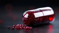 Red glitter spilling from transparent medical capsule on dark background with bokeh effect, macro photography for pharmaceutical or healthcare concept.