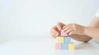 Female hands arranging colorful wooden blocks on white surface for business planning and strategy development concepts.