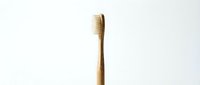 Single bamboo toothbrush with natural bristles isolated on white background for eco-friendly dental care and sustainable oral hygiene products.