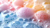 Colorful soap bubbles with water droplets floating on sudsy foam surface, ideal for cleaning product marketing, hygiene concepts, and wellness advertising campaigns.