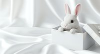 Cute white rabbit toy peeking from white box on soft fabric background, isolated design element for children's products, greeting cards, nursery decor, and Easter themed projects.