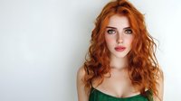 Young redhead woman with curly hair wearing green top against white background. Portrait of attractive female model with natural makeup and confident expression.