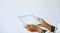 Person with medium skin tone holding blank tablet device against white background for app mockup and digital technology concepts.