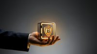 Businessman hand holding glowing shield security icon with padlock symbol, representing data protection and cybersecurity solutions for business.