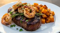 Grilled steak with shrimp, roasted potatoes and fresh herbs on white plate, fine dining restaurant meal for gourmet food and culinary concepts.