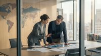 Professional businesswoman and businessman collaborating over documents in modern office with world map, discussing strategy and planning projects together.