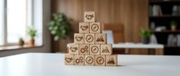 Wooden blocks stacked in pyramid form with business icons including gears, charts, and symbols representing strategy, growth, and corporate success for organizational development.