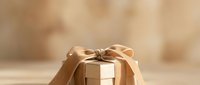 Wrapped gift box with golden ribbon bow on neutral beige background, suitable for holiday, birthday, and celebration marketing materials.