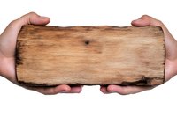 Hands holding rustic wooden plank with rough texture and natural grain pattern against white background, isolated mockup for signage and design projects.