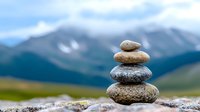 Balanced stack of zen stones against majestic mountain landscape with snow peaks and green valley, symbolizing harmony, meditation and spiritual balance.