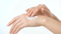 Caucasian woman applying moisturizing cream or lotion to hand for skincare routine, cosmetics and beauty treatment on white background.