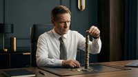 Serious middle-aged Caucasian businessman in white shirt and tie holding vintage telephone receiver at wooden desk in dark office interior.