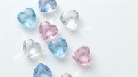 Collection of heart-shaped gemstones in pastel colors including pink, blue and clear crystals arranged on white background for jewelry design.