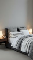 Contemporary bedroom interior with neatly arranged bed featuring gray striped comforter, white sheets, and decorative pillows. Wooden nightstands with warm table lamps and minimalist decor.